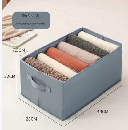 Drawer-style storage box with multiple compartments organizing folded clothes and jeans in light gray and blue colors