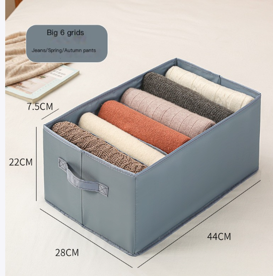 Drawer-style storage box with multiple compartments organizing folded clothes and jeans in light gray and blue colors