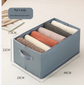 Drawer-style storage box with multiple compartments organizing folded clothes and jeans in light gray and blue colors