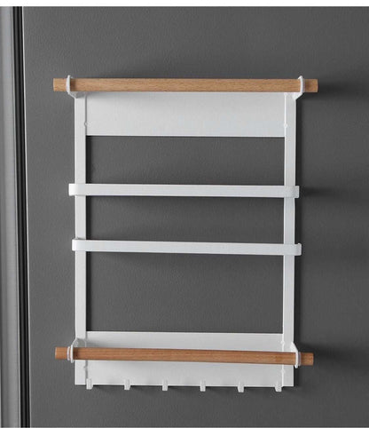 Magnetic kitchen towel rack and storage organizer mounted on refrigerator holding paper towels and spices